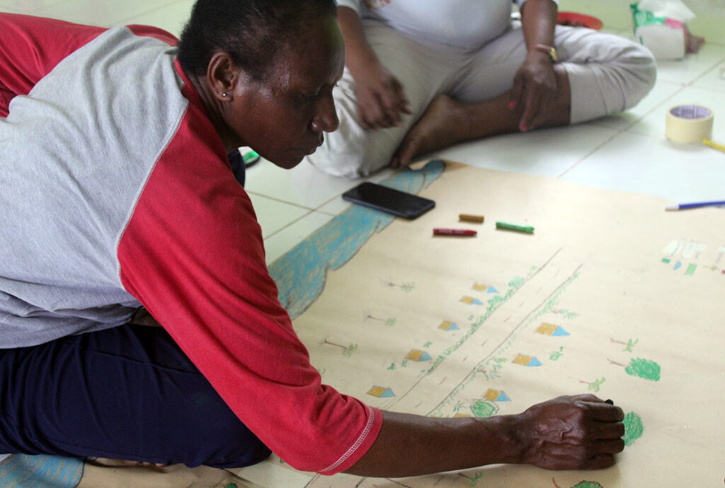 Ibu Elisabeth working on a community map recording areas of concern in her village during a session at the Women’s School. (Photo: Perkumpulan Petrus Vertenten Msc Papua)
