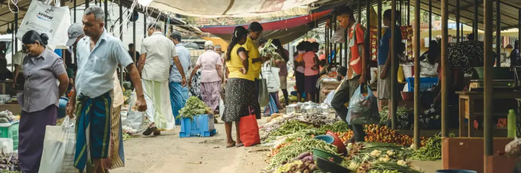 People shopping for fresh vegetables at an outdoor market in Sri Lanka