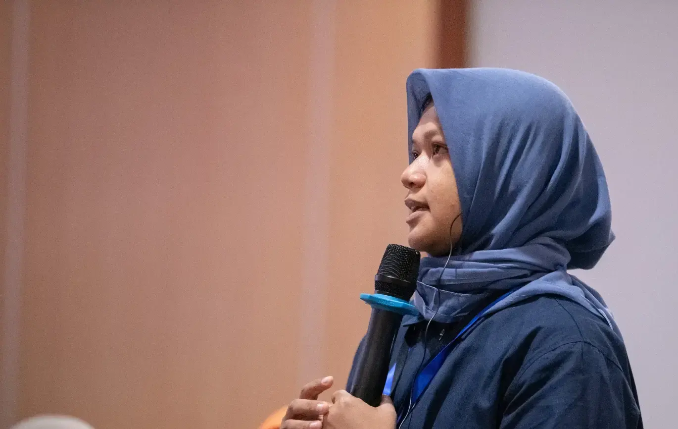 A Muslim woman in a blue hijab speaking into a microphone at a forum in the Philippines