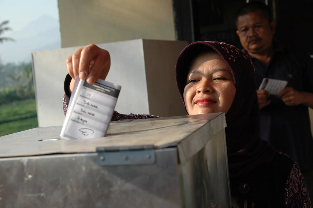 woman casting vote dropping ballot in box