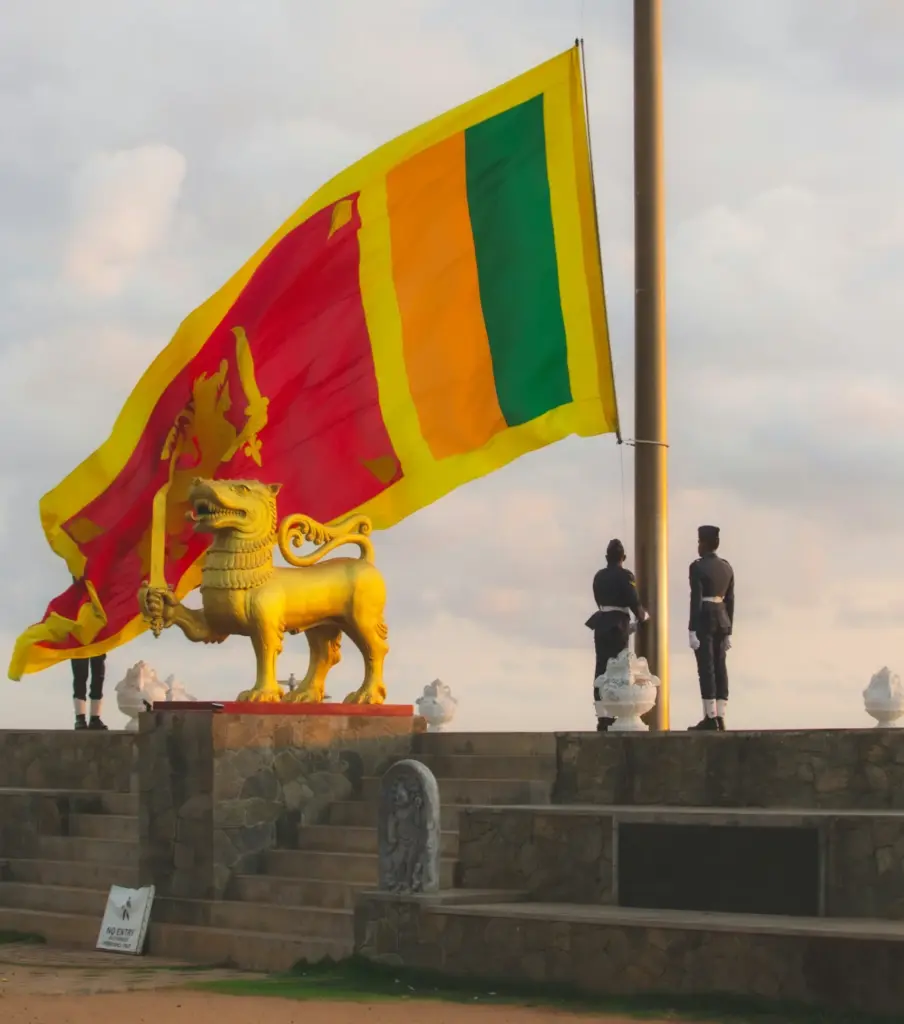 Sri lankan flag with statue and guards at sunrise