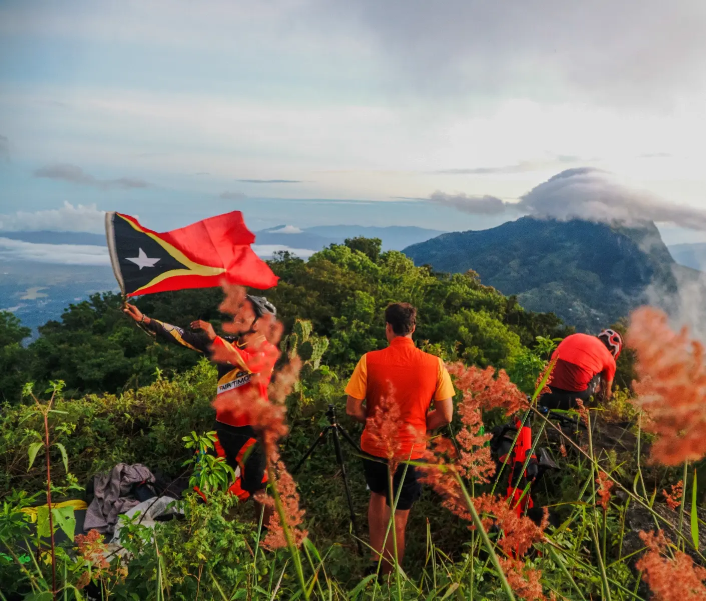 man waving timor leste flag on top of hill